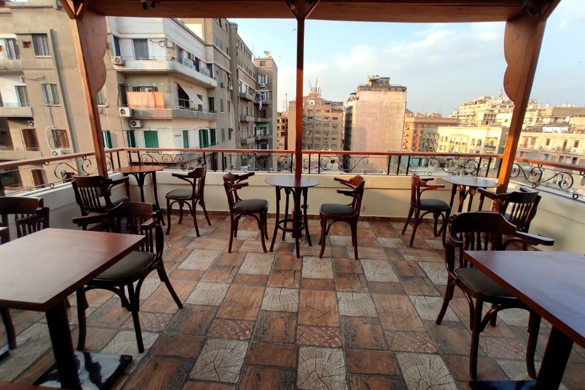 Cairo House Hostel terrace with tables and chairs overlooking Downtown Cairo buildings