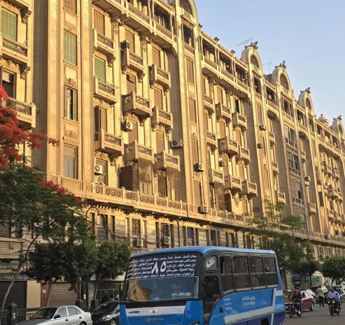 Belle-epoque apartment building and a red flame tree on a Downtown Cairo street at sunset
