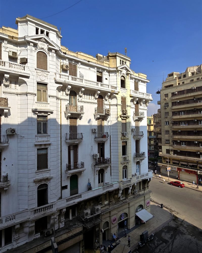 White belle-epoque building on a Downtown Cairo street corner under a blue sky
