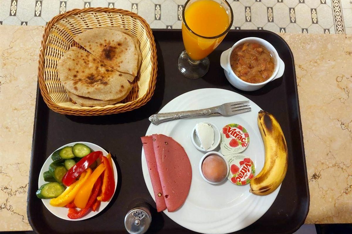 Breakfast tray with Egyptian bread, a small bowl, egg, vegetables, banana and orange juice