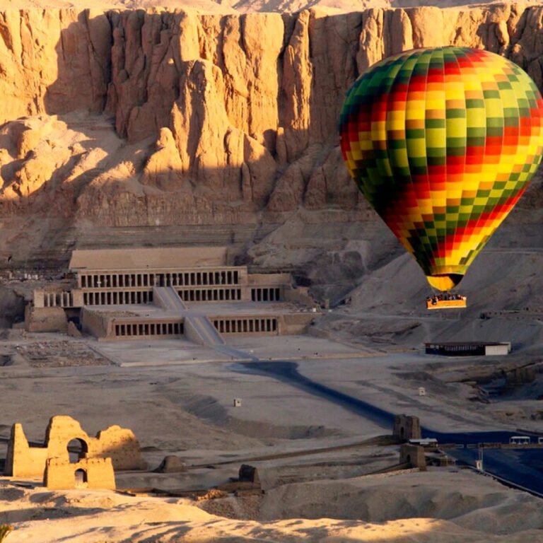 Colourful hot air balloon with passengers above Deir el-Bahari, Luxor